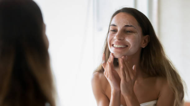 istock Smiling young woman scrub face with beauty mask 1207696922