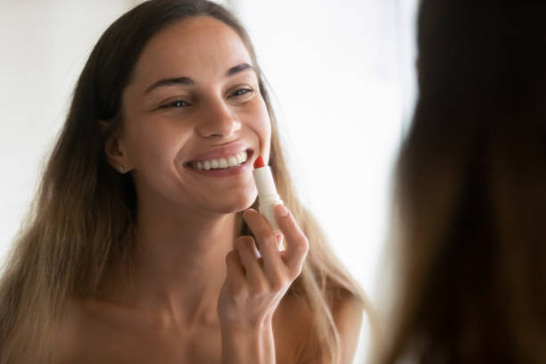 istock Smiling young woman get ready apply red lipstick 1207696925