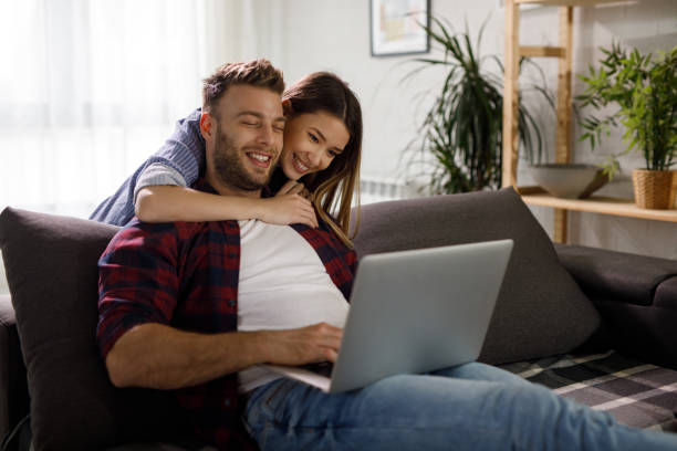 istock Young couple using a laptop while relaxing on the sofa at home 1207697173