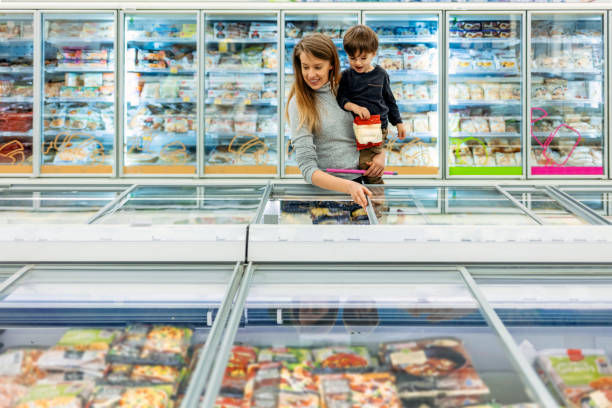 giovane madre con bambino che sceglie i prodotti al supermercato - cibi surgelati foto e immagini stock