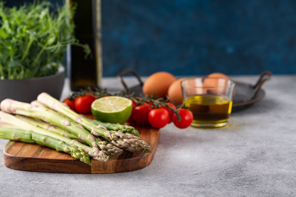 Variety of fresh, colorful, and raw vegetables on a white wooden table. Beetroots, mushrooms, broccoli, asparagus, potatoes, sweet potatoes, and corn. Bright background.
