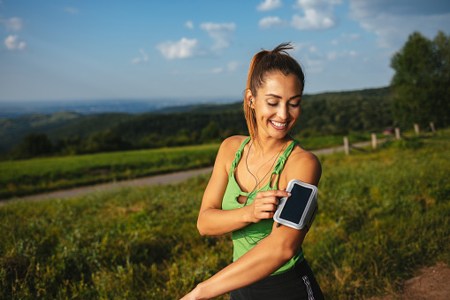 Female athlete adjusting her fitness tracker before a running session in nature