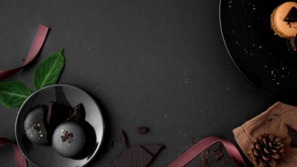 istock Overhead shot of dark chocolate macarons on black plate on dark table 1207702500