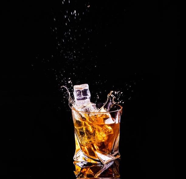 istock Whiskey with splash on black background, brandy in a glass 1207705824