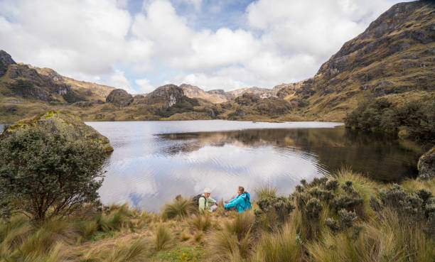 Senior couple siting and enjoying beautiful nature  at Lake in  El Cajas national park, Ecuador stock photo