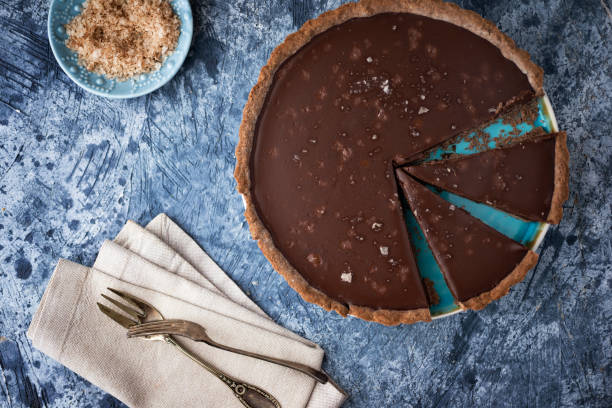 tarte au chocolat avec le sel de mer sur la table bleue - tarte sucrée photos et images de collection