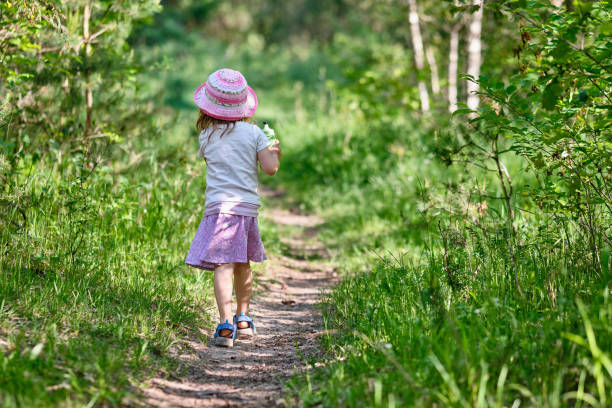 vista trasera de niña caminando en naturaleza verde - children only tree area exploration freshness fotografías e imágenes de stock