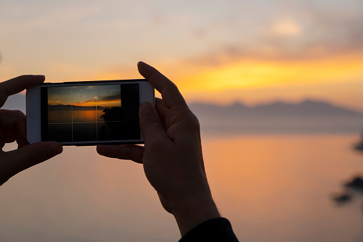 Man photographing sunset over the sea with camera phone, Antalya, Turkey
