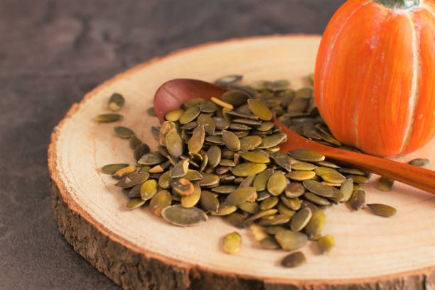 istock Raw pumpkin seeds on wooden background 1207707560
