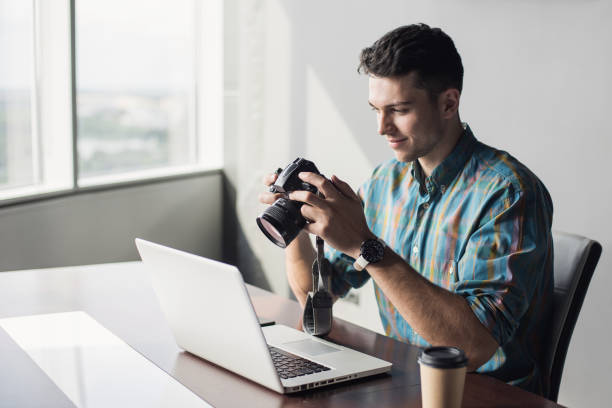 istock Photographer looking at photos and using laptop computer 1207708292