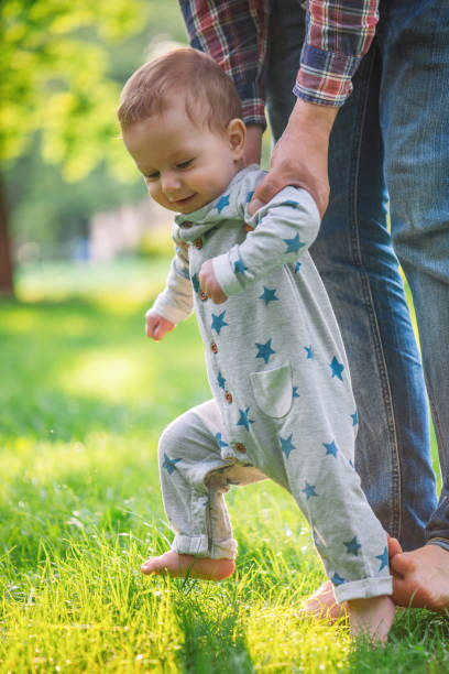 istock Baby boy is happy with his first steps supported by his father on a summer meadow 1207710302
