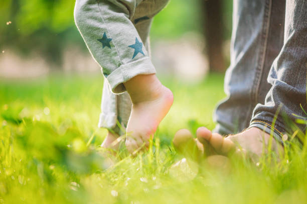 istock Baby boy is happy with his first steps supported by his father on a summer meadow 1207710815