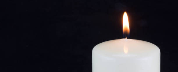 una fiamma di candela bianca che brucia nel buio su sfondo nero con spazio di copia per il testo. - necrologio immagine foto e immagini stock