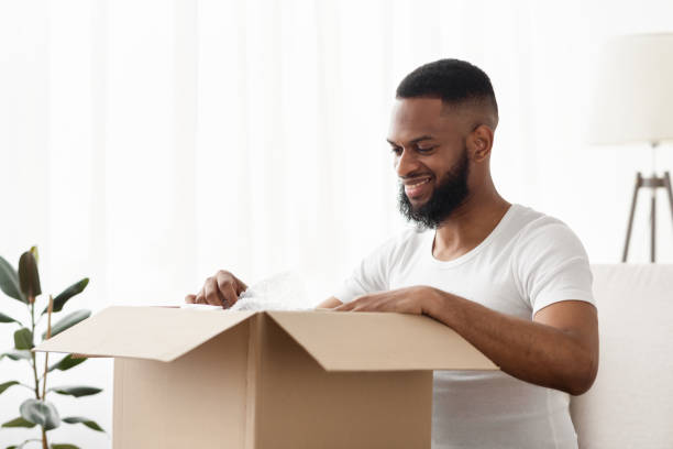 istock Happy african american guy opening delivery at home 1207712967