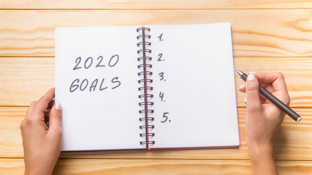 istock Woman writing in planner 2020 goals, wooden table 1207714217