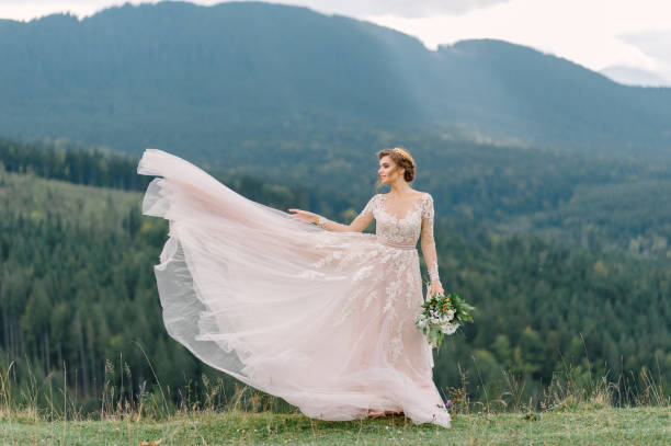 whirling bride holding veil skirt of wedding dress at pine forest - wedding dress bouquet wedding bride imagens e fotografias de stock