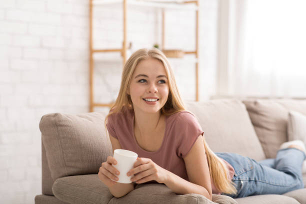 istock Cheerful blonde girl drinking tea at home 1207715111