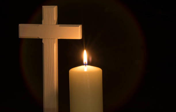 istock Burning candle and cross on black background 1207715453