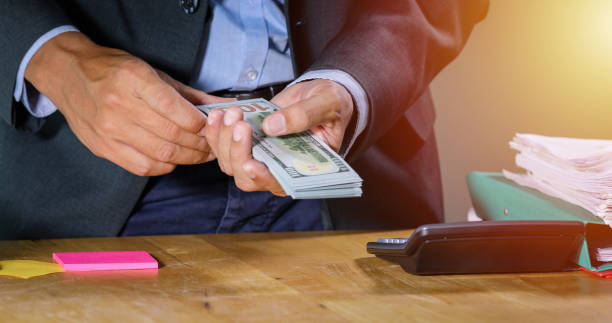 istock Asian Businessmen count money and plan finances for projects and use calculators for analysis project documents and graph financial diagram working in the background on office table 1207715613