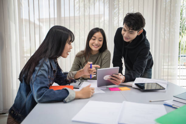 istock Group Asian  Students Smile and reading book and using notebook for helps to share ideas in the work and project. And also review the book before the exam 1207715616