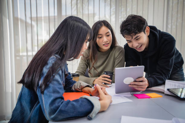 istock Group Asian  Students Smile and reading book and using notebook for helps to share ideas in the work and project. And also review the book before the exam 1207715657