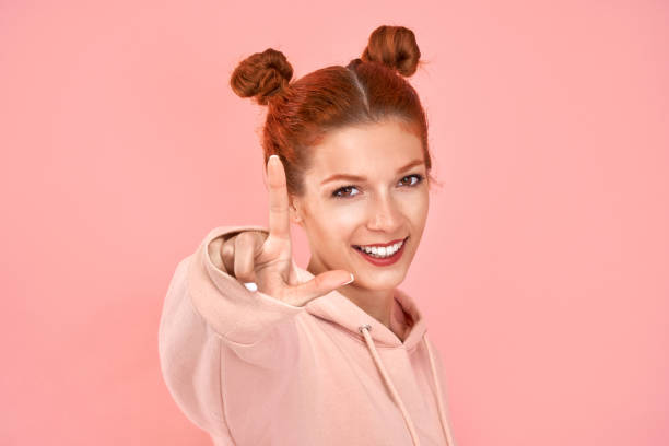 istock Young ginger woman showing one finger over pink background. Counting gesture 1207716601