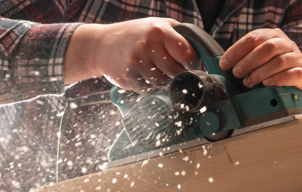istock Close-up of carpenter s hands and plane tool. 1207717925
