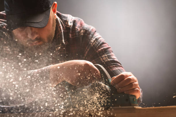 istock Close-up of carpenter s hands and plane tool. 1207717928