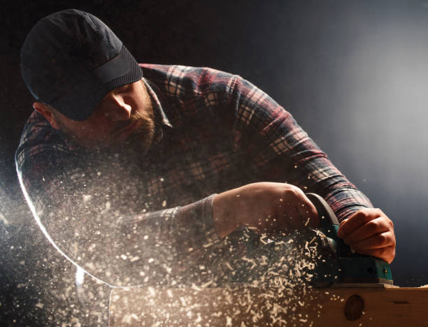 istock Close-up of carpenter s hands and plane tool. 1207717933