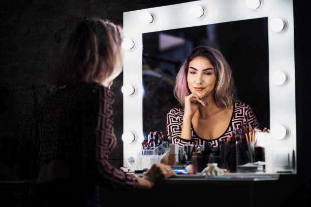 Be confident with what you see in the mirror! Young, confident woman looking at the mirror after putting a makeup. backstage mirror stock pictures, royalty-free photos & images
