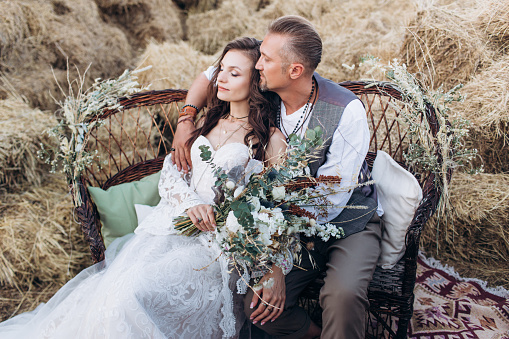 The groom dressed in the style of boho gently kisses the bride.-Image