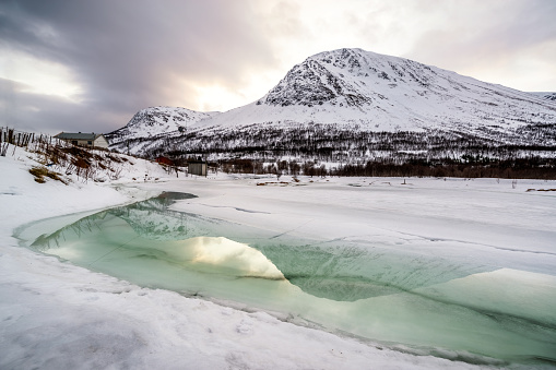 frozen river with water reflection in Oldervik, Trom County, Norway