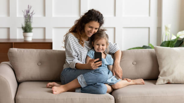 szczęśliwa ładna mama przytula małą córkę, robiąc selfie na telefonie komórkowym. - mothers audio zdjęcia i obrazy z banku zdjęć