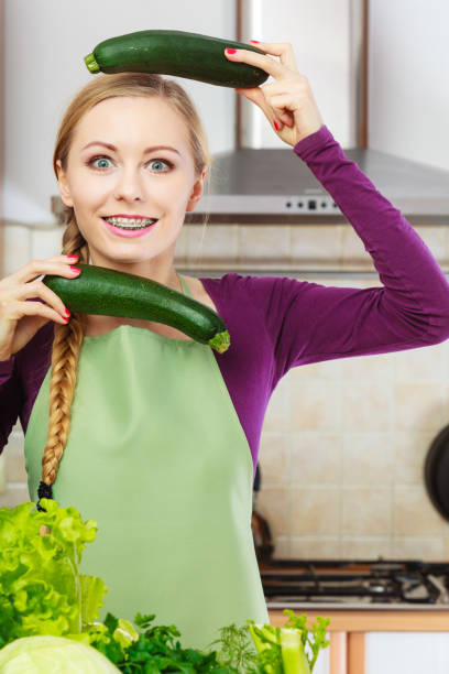 istock Woman in kitchen holds zucchini vegetable 1207723272