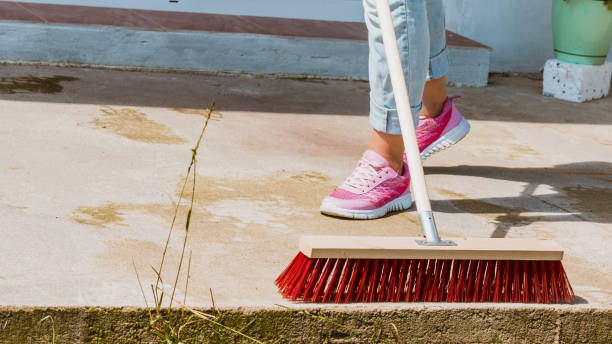 istock Woman using broom to clean up backyard patio 1207725948
