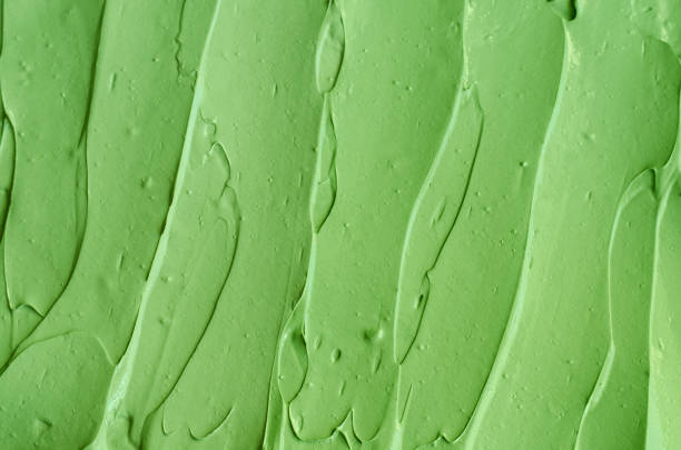 istock Green cosmetic clay (cucumber facial mask, avocado face cream, green tea body wrap) texture close up, selective focus. Abstract background with brush strokes 1207727480