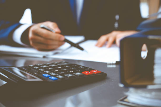 istock Binders with papers waiting to be processed with businessman or bookkeeper back in blur. Accounting planning budget. Audit, insurance and business concept 1207727599