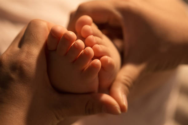 Mother holds the baby's feet