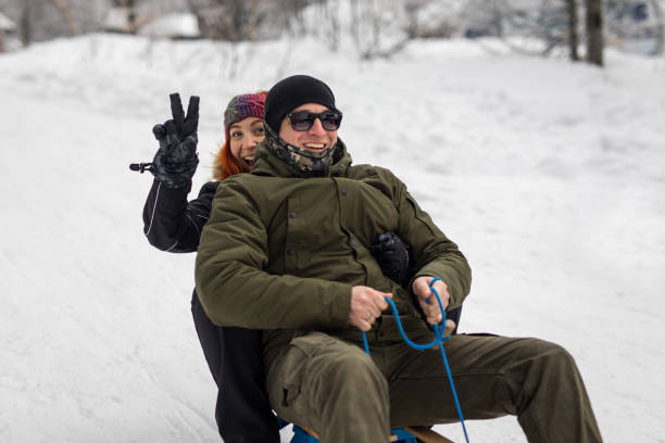 istock Young couple sliding on sled in mountain resort 1207729620