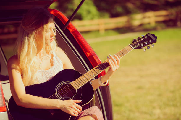 istock Hippie woman playing guitar in van car 1207731500