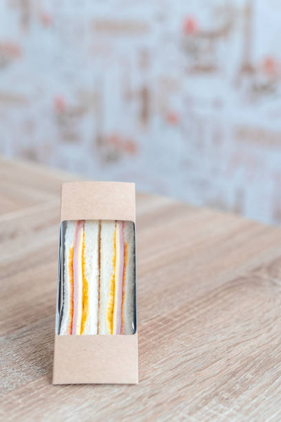 istock Cheese sandwiches, wrapped in plastic, put in a paper box, put on the table, white background 1207736962