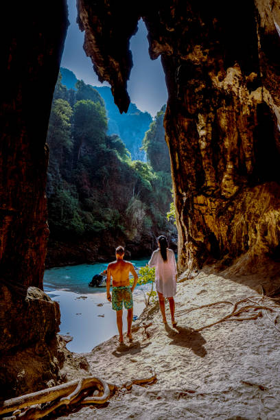 Hidden beach with huge cave near Koh Poda Island Krabi Thailand,men at a limestone cliff looking out over the secret beach at Koh Poda Krabi Thailand Hidden beach with huge cave near Koh Poda Island Krabi Thailand,men at a limestone cliff looking out over the secret beach at Koh Poda Krabi Thailand, Asia koh poda stock pictures, royalty-free photos & images