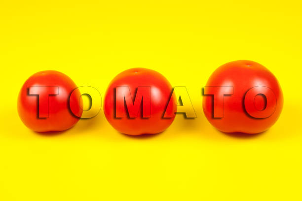 istock Beautiful fresh tomatoes isolated on yellow background. Word TOMATO 1207739135