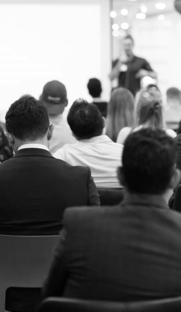 istock Business man making a presentation at office. Business executive delivering a presentation to his colleagues during meeting or in-house workshop. Rear view. Business and entrepreneurship. 1207743570