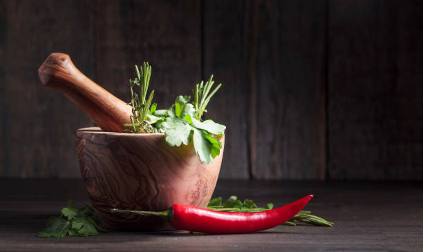 pepe rosso ed erbe varie su un vecchio tavolo di legno. - mortar and pestle herb coriander seed cilantro foto e immagini stock