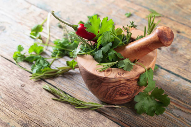 pepe rosso ed erbe varie su un vecchio tavolo di legno. - mortar and pestle herb coriander seed cilantro foto e immagini stock