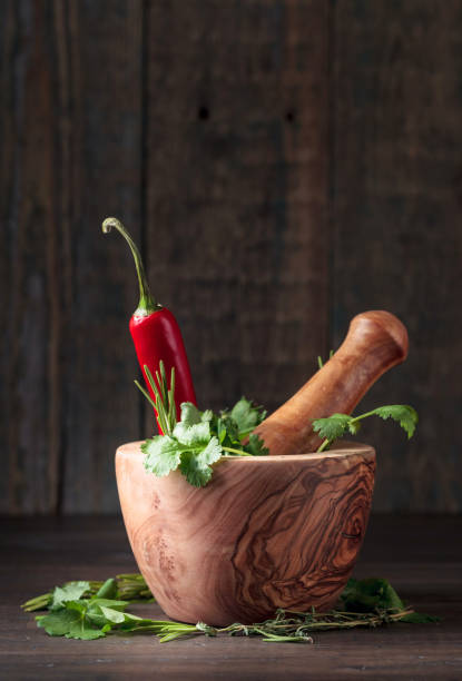 pepe rosso ed erbe varie su un vecchio tavolo di legno. - mortar and pestle herb coriander seed cilantro foto e immagini stock