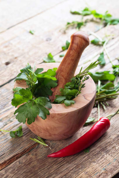 pepe rosso ed erbe varie su un vecchio tavolo di legno. - mortar and pestle herb coriander seed cilantro foto e immagini stock