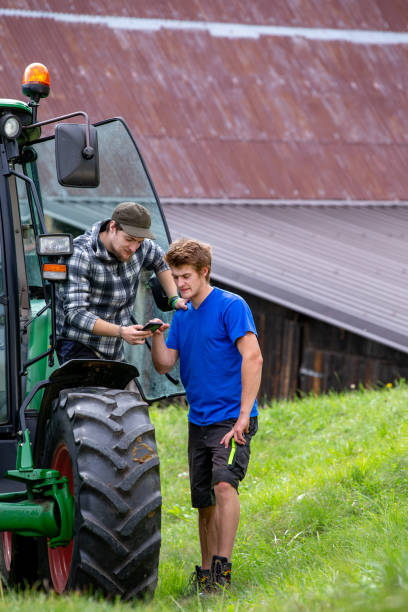 istock Two Young Workers on a Farm Checking the Phone while Resting - Stock Photo 1207746858