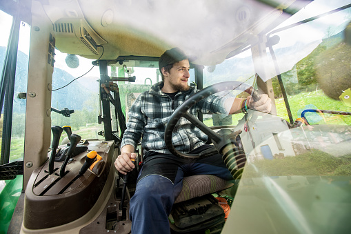 Shot Of Farmers Son Through the Front Window of a Tractor Enjoying the View - Stock Photo